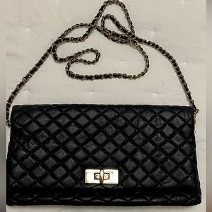 Black quilted fold over clutch with gold hardware. Removable strap. Snap closure